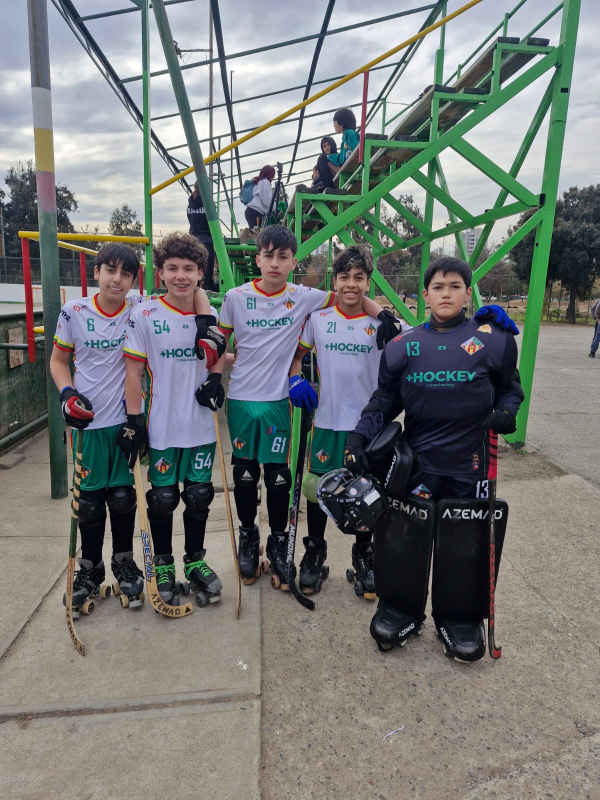 Los jugadores de hockey patín de Talcahuano con su equipamiento completo —patines, canilleras y camisetas del club— junto a la cancha en Santiago