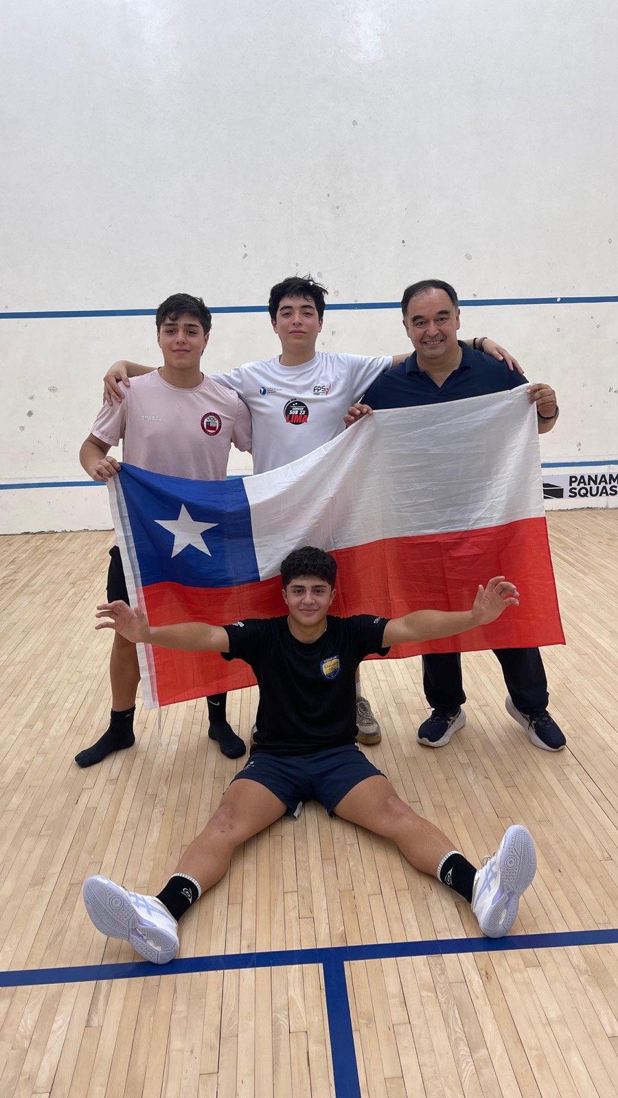 Los tres jugadores chilenos de squash Sub-19 junto a su técnico Cristian Schulz, sosteniendo la bandera de Chile en El Salvador