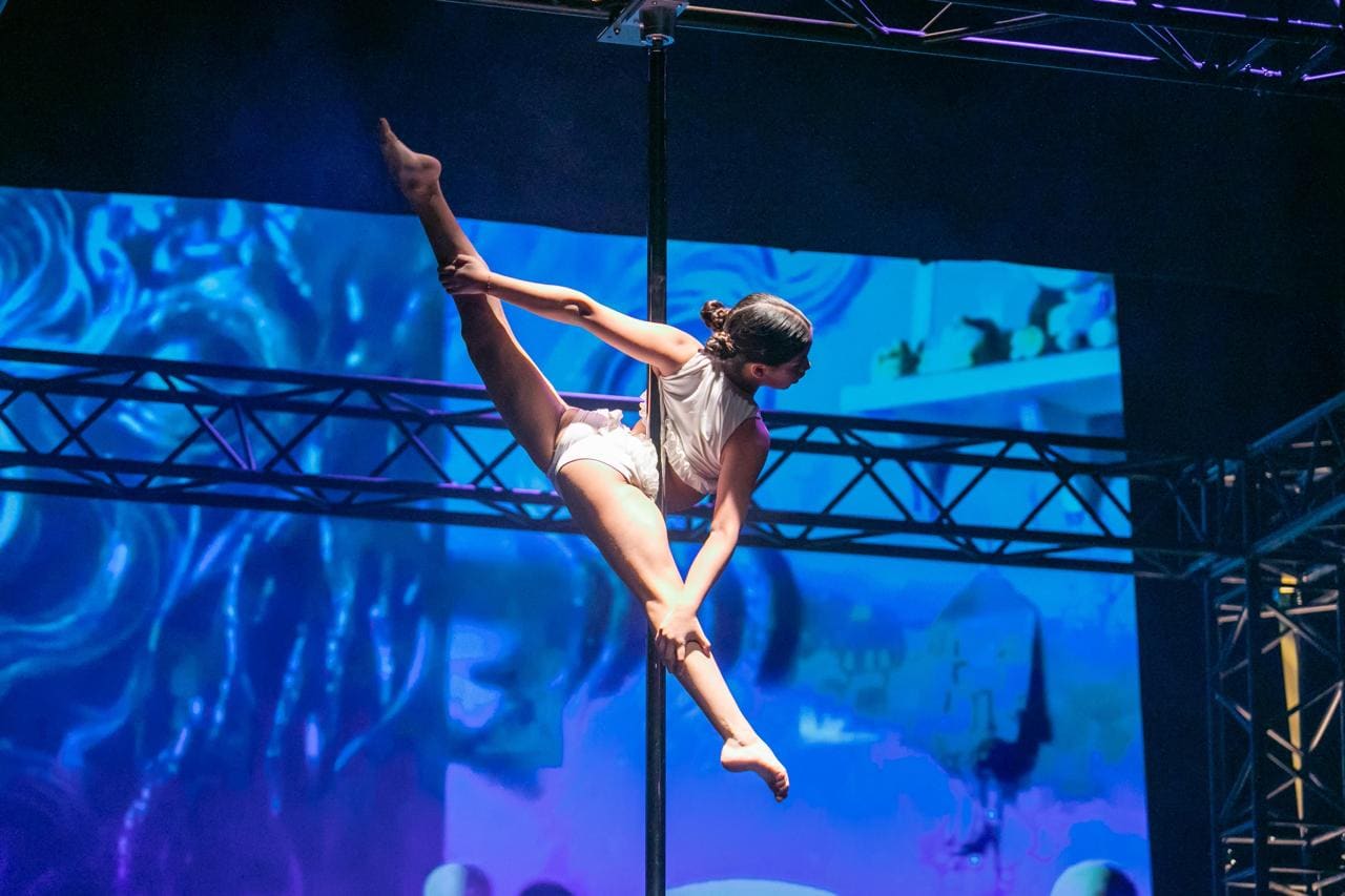 Amparo Hall ejecutando una figura de Pole Sport sobre la barra durante su rutina en el escenario